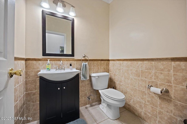 bathroom featuring tile patterned flooring, wainscoting, toilet, and tile walls