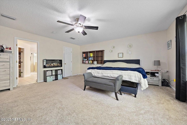 carpeted bedroom featuring visible vents, a ceiling fan, and a textured ceiling
