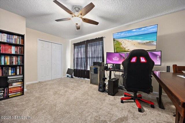 carpeted home office with a textured ceiling and ceiling fan