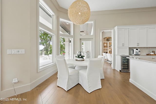 dining room with wine cooler, wood finished floors, and a healthy amount of sunlight