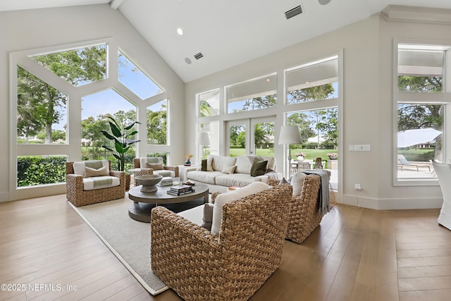 living area featuring high vaulted ceiling, baseboards, hardwood / wood-style floors, and visible vents