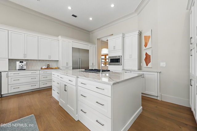 kitchen with a center island, white cabinets, built in appliances, ornamental molding, and recessed lighting