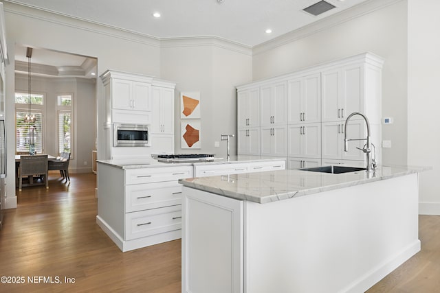 kitchen featuring a sink, stainless steel appliances, white cabinetry, wood finished floors, and ornamental molding