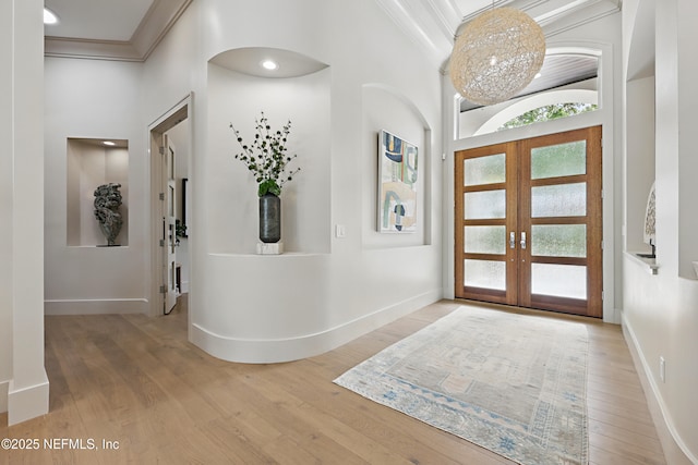 foyer entrance featuring ornamental molding, french doors, and wood finished floors