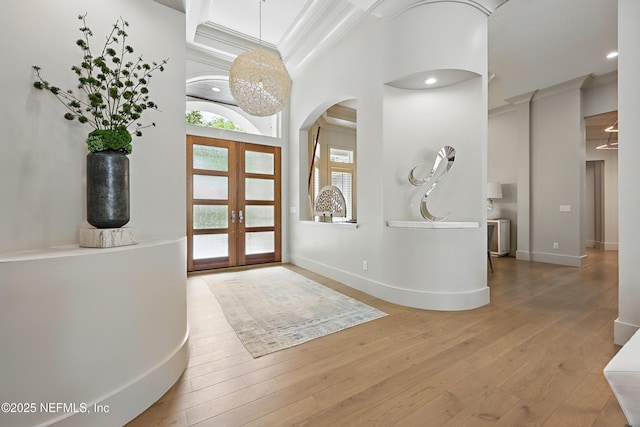 foyer entrance with crown molding, wood-type flooring, arched walkways, french doors, and recessed lighting