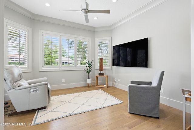 living area with baseboards, ceiling fan, ornamental molding, and a wealth of natural light
