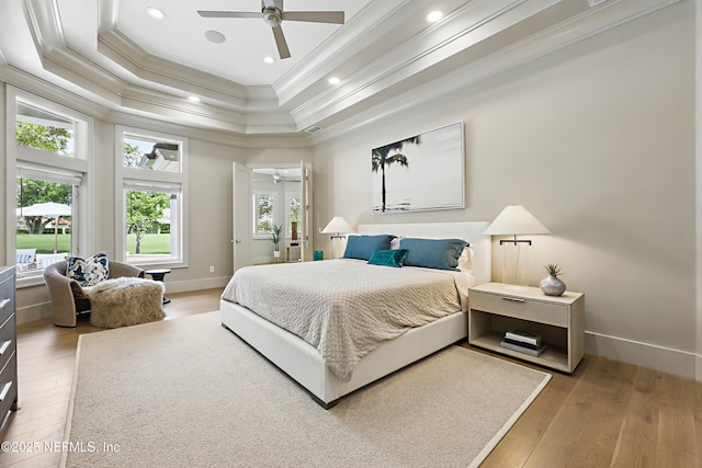 bedroom with crown molding, a raised ceiling, baseboards, and light wood-style floors