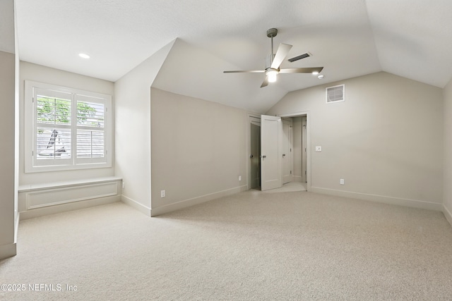 unfurnished bedroom featuring carpet floors, baseboards, lofted ceiling, and visible vents