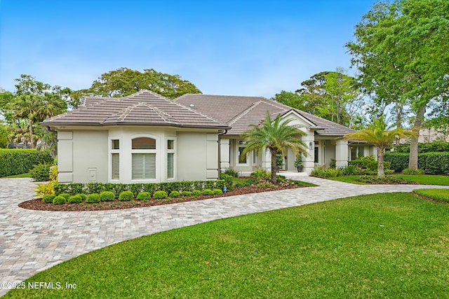 view of front of house with stucco siding, a tile roof, and a front yard