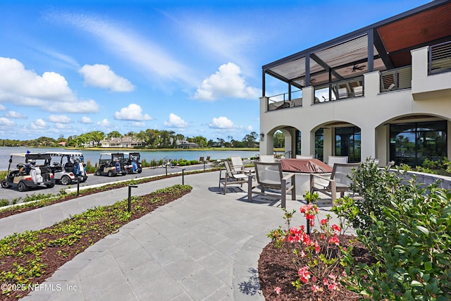view of patio / terrace with a ceiling fan, a water view, and a balcony