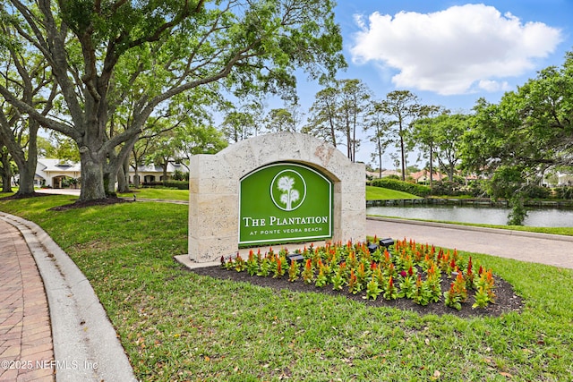 community / neighborhood sign with a water view and a yard