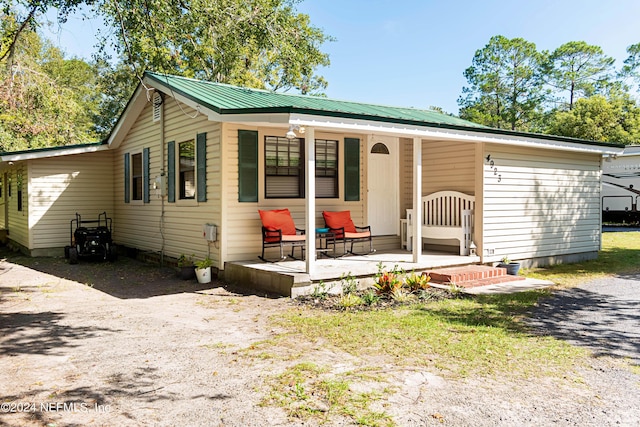 view of front of house with covered porch, driveway, and metal roof