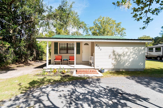 ranch-style home featuring a porch and metal roof