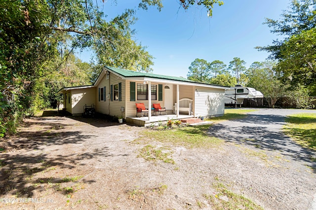 view of front of property with metal roof and dirt driveway