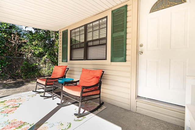 view of patio featuring a porch and fence