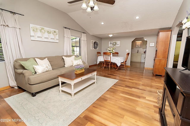 living room with ceiling fan, arched walkways, vaulted ceiling, baseboards, and light wood-style floors