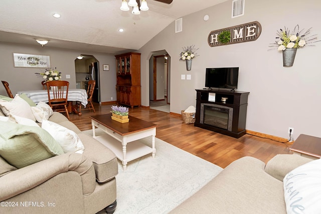 living area with arched walkways, ceiling fan, wood finished floors, and visible vents