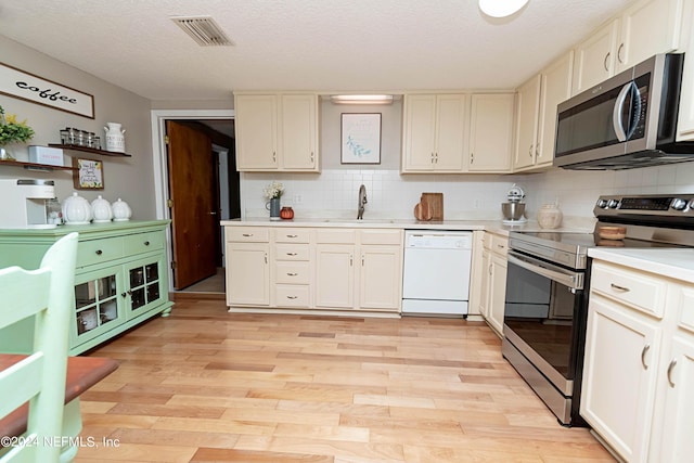 kitchen featuring decorative backsplash, visible vents, appliances with stainless steel finishes, a sink, and light countertops