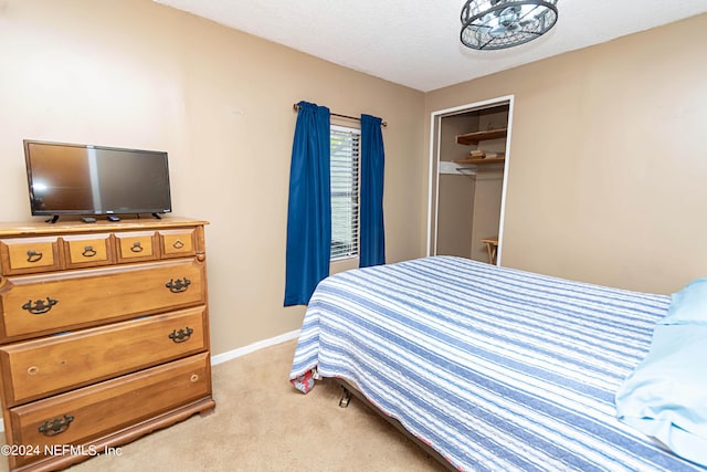 bedroom featuring a textured ceiling, baseboards, light colored carpet, and a closet