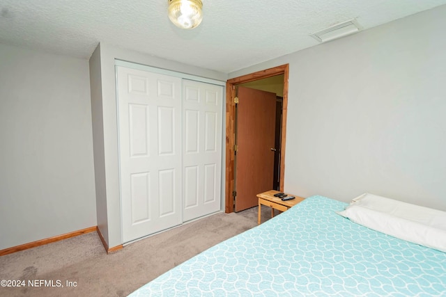 bedroom featuring light carpet, a closet, a textured ceiling, and visible vents