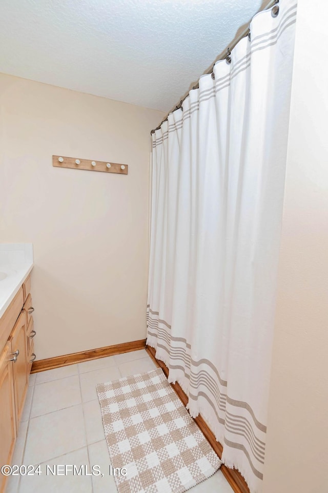 full bath featuring tile patterned floors, baseboards, and vanity