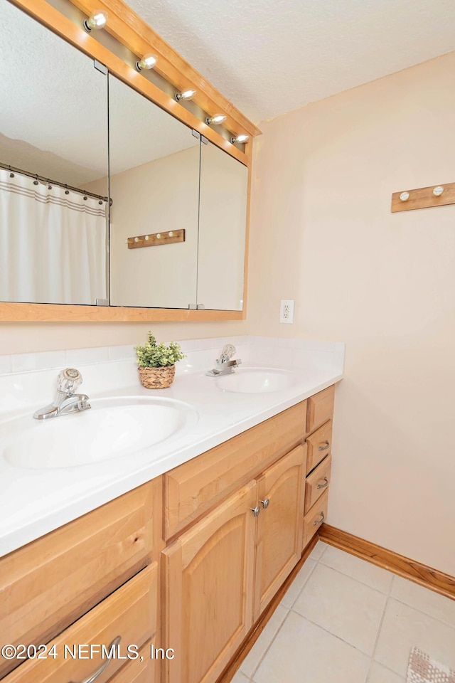 bathroom featuring double vanity, baseboards, a sink, and tile patterned flooring