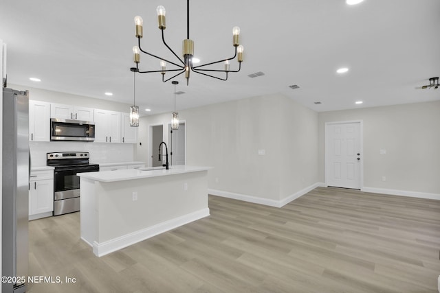 kitchen with recessed lighting, light countertops, a sink, light wood finished floors, and stainless steel appliances