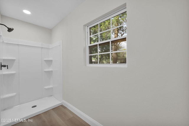 bathroom featuring a shower, baseboards, and wood finished floors