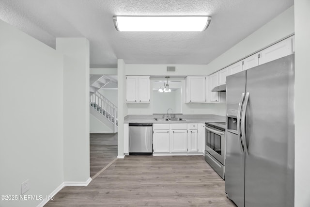 kitchen featuring a sink, appliances with stainless steel finishes, a textured ceiling, and white cabinetry