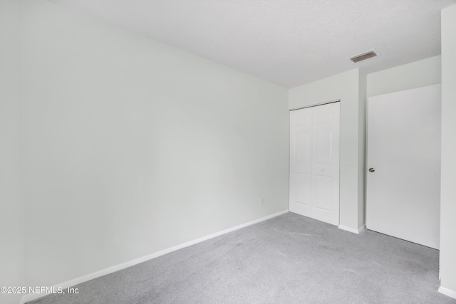 unfurnished bedroom with carpet floors, baseboards, visible vents, and a closet
