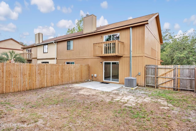 back of house featuring central AC unit, a chimney, a patio area, and a balcony
