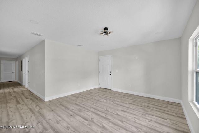 spare room featuring baseboards, wood finished floors, and visible vents