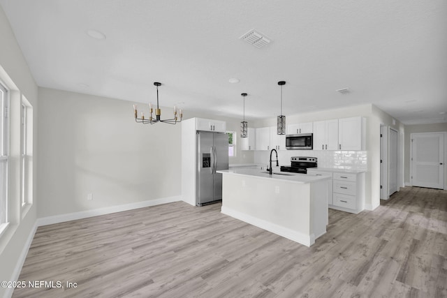 kitchen with a chandelier, appliances with stainless steel finishes, a sink, and light wood-style flooring