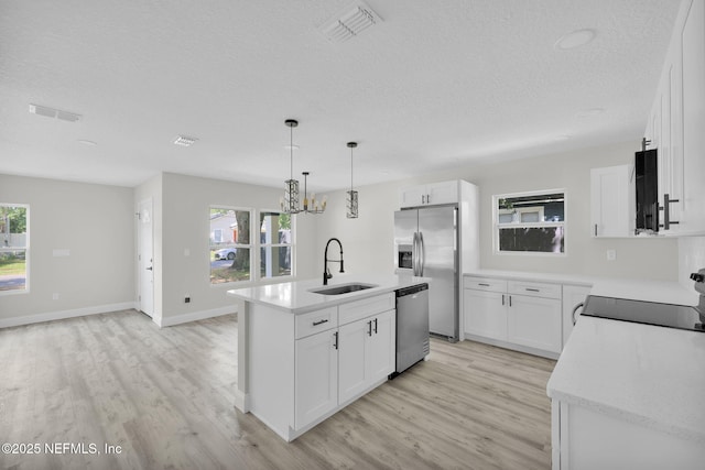 kitchen featuring a sink, light wood finished floors, appliances with stainless steel finishes, and a textured ceiling