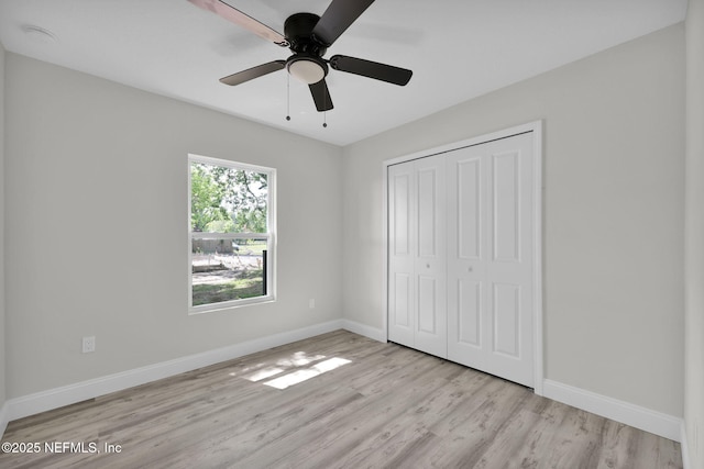 unfurnished bedroom with a closet, baseboards, a ceiling fan, and light wood-type flooring