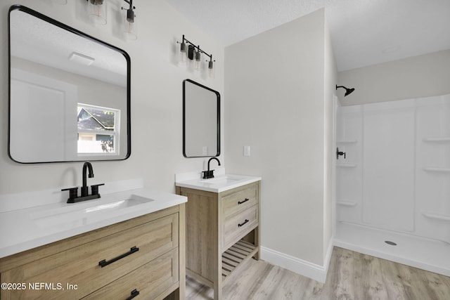 full bathroom with baseboards, a sink, walk in shower, and wood finished floors
