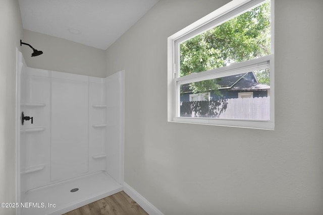 bathroom featuring baseboards, wood finished floors, and a shower