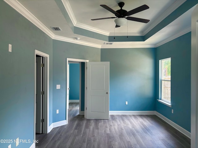unfurnished bedroom with crown molding, a tray ceiling, wood finished floors, and visible vents