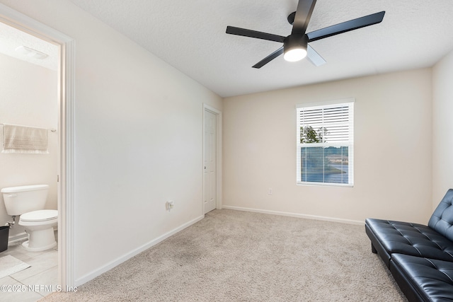 unfurnished room with baseboards, a ceiling fan, a textured ceiling, and light carpet