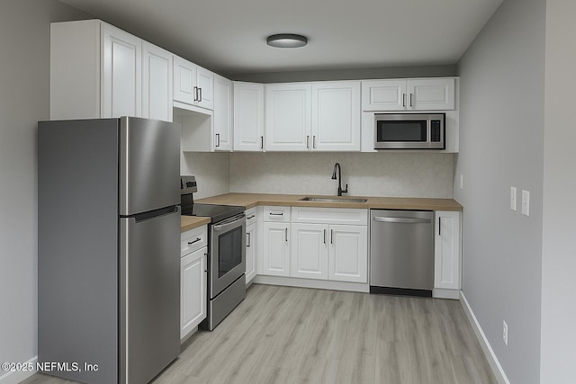 2103 W 14th St, Jacksonville, FL 32209 - kitchen with appliances with stainless steel finishes, wooden counters, light wood-type flooring, a sink, and white cabinets
