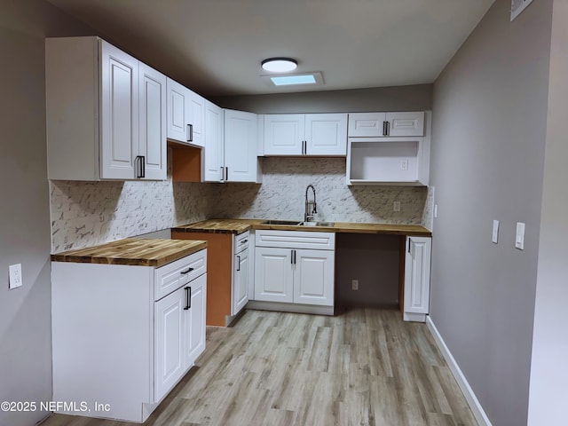 2103 W 14th St, Jacksonville, FL 32209 - kitchen featuring wooden counters, a sink, light wood finished floors, tasteful backsplash, and white cabinetry