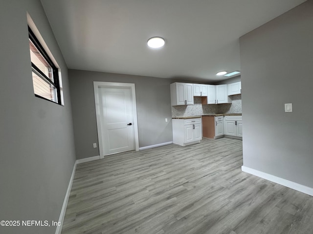 2103 W 14th St, Jacksonville, FL 32209 - kitchen with baseboards, white cabinetry, and light wood finished floors
