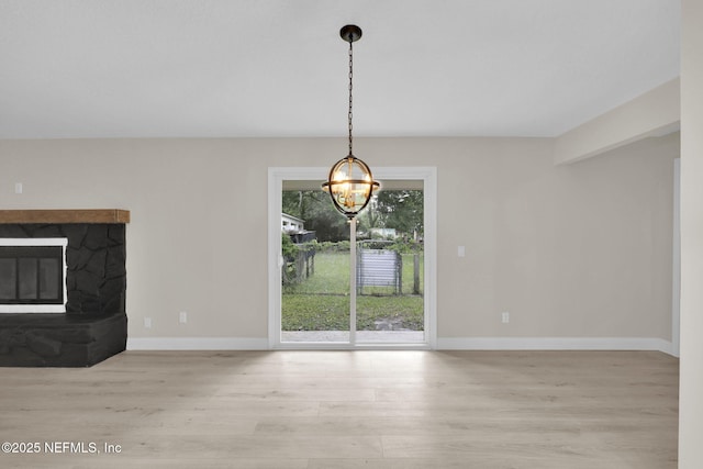 unfurnished dining area featuring baseboards, wood finished floors, and a chandelier