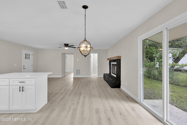 kitchen featuring visible vents, light wood-style flooring, white cabinets, and decorative light fixtures