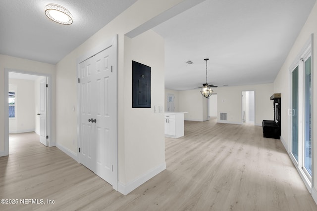 hall with baseboards, light wood-style flooring, electric panel, and visible vents