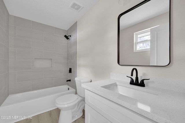 bathroom with visible vents, vanity, wood finished floors, bathing tub / shower combination, and toilet