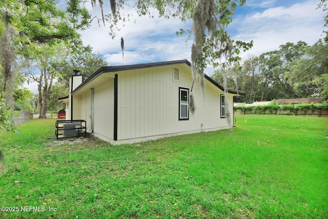 view of side of home with a yard, fence, and a chimney