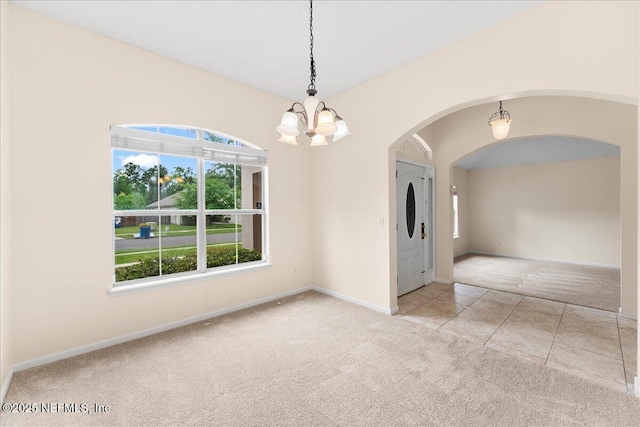 carpeted empty room with arched walkways, baseboards, and a chandelier