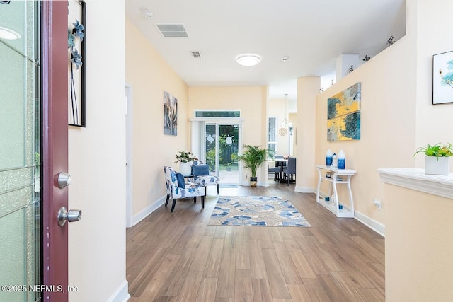 hallway featuring baseboards, wood finished floors, and visible vents