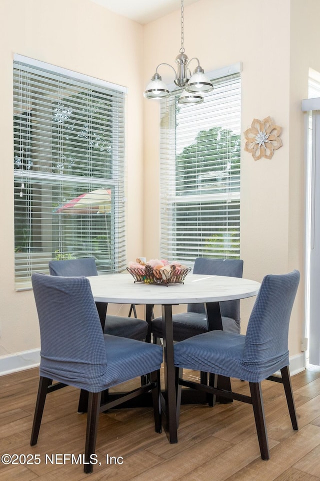 dining room featuring baseboards, wood finished floors, and a notable chandelier